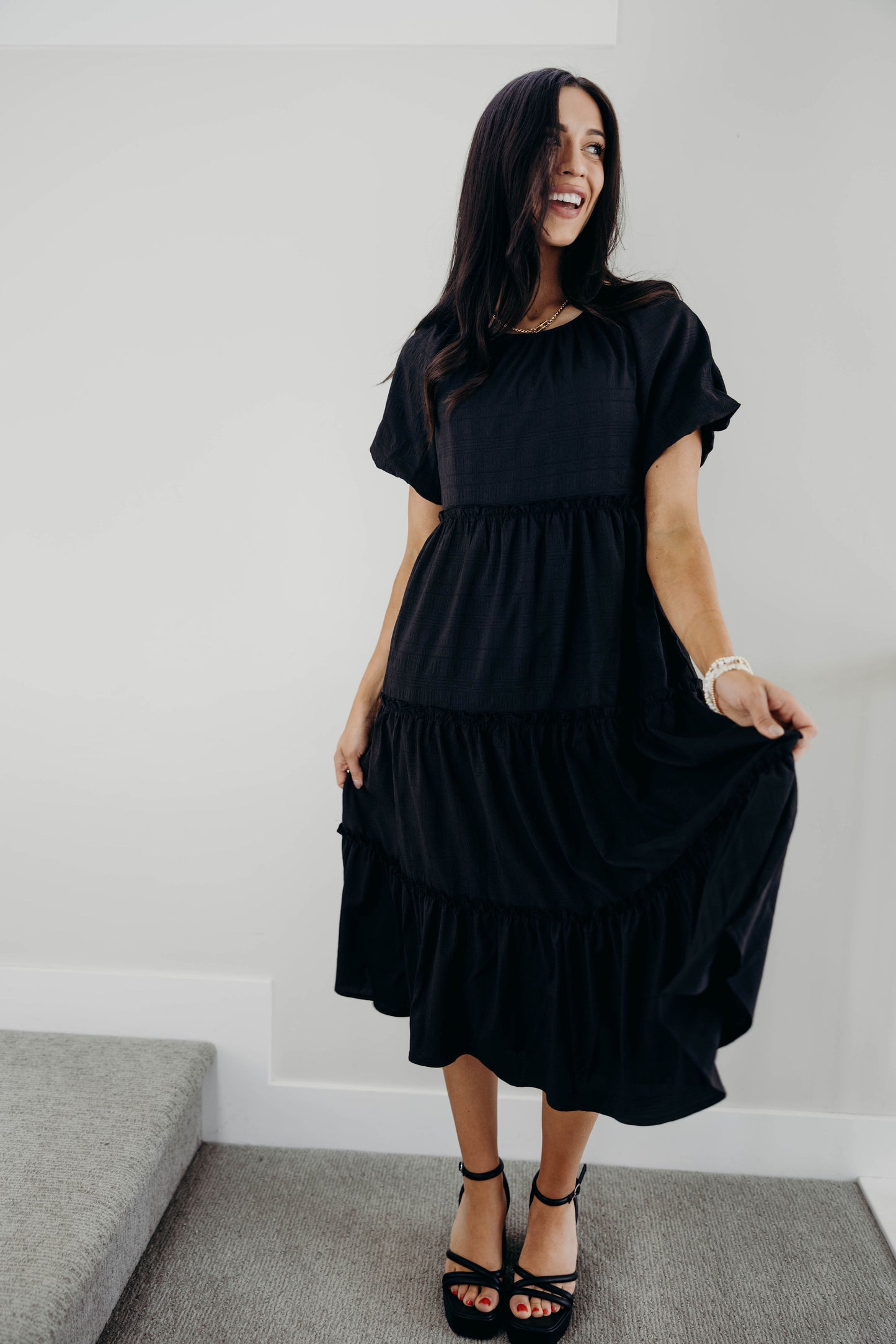Black midi dress with round neckline and short sleeves.