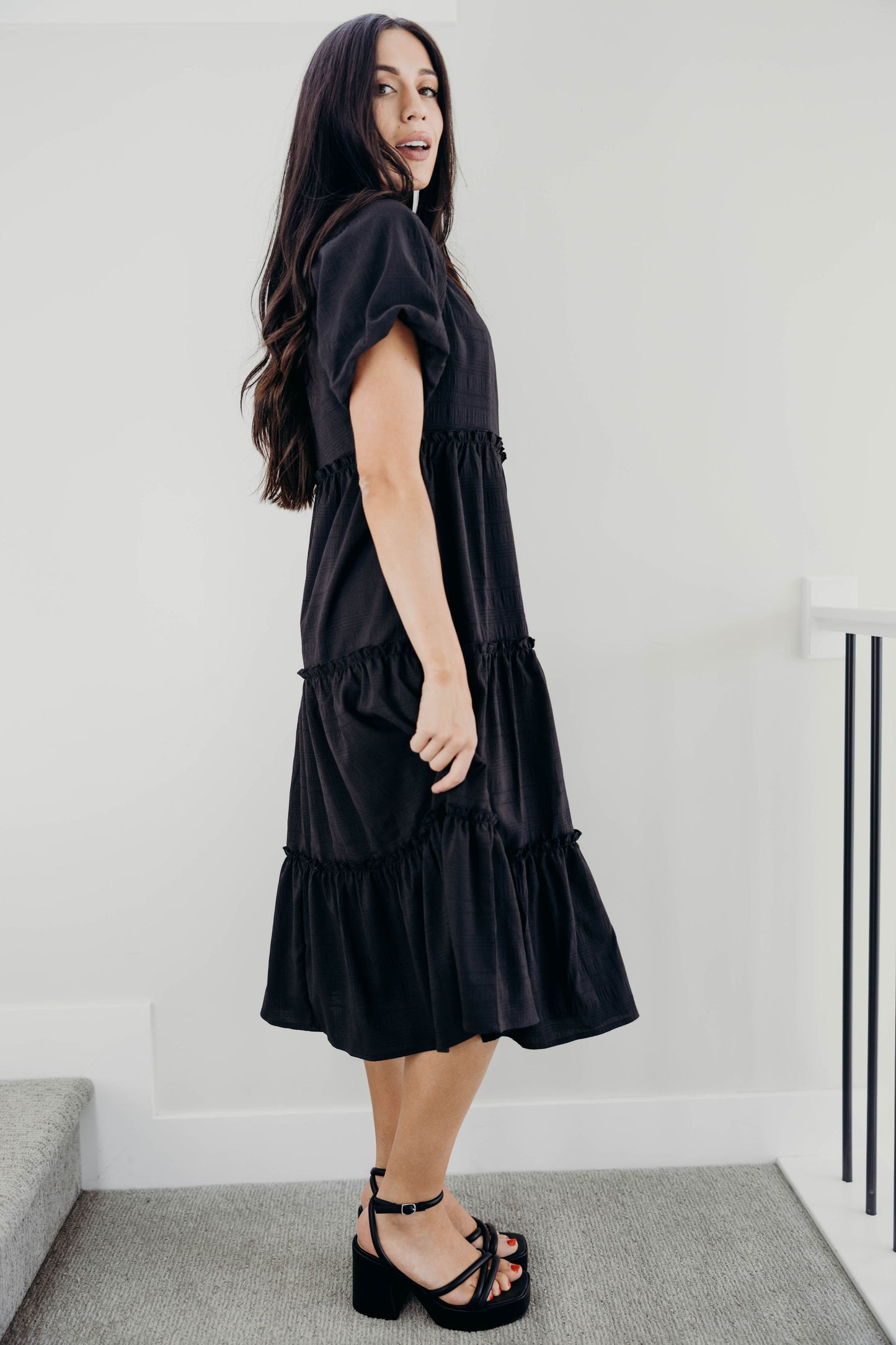 Ruffle tiered black textured dress with short puff sleeves.