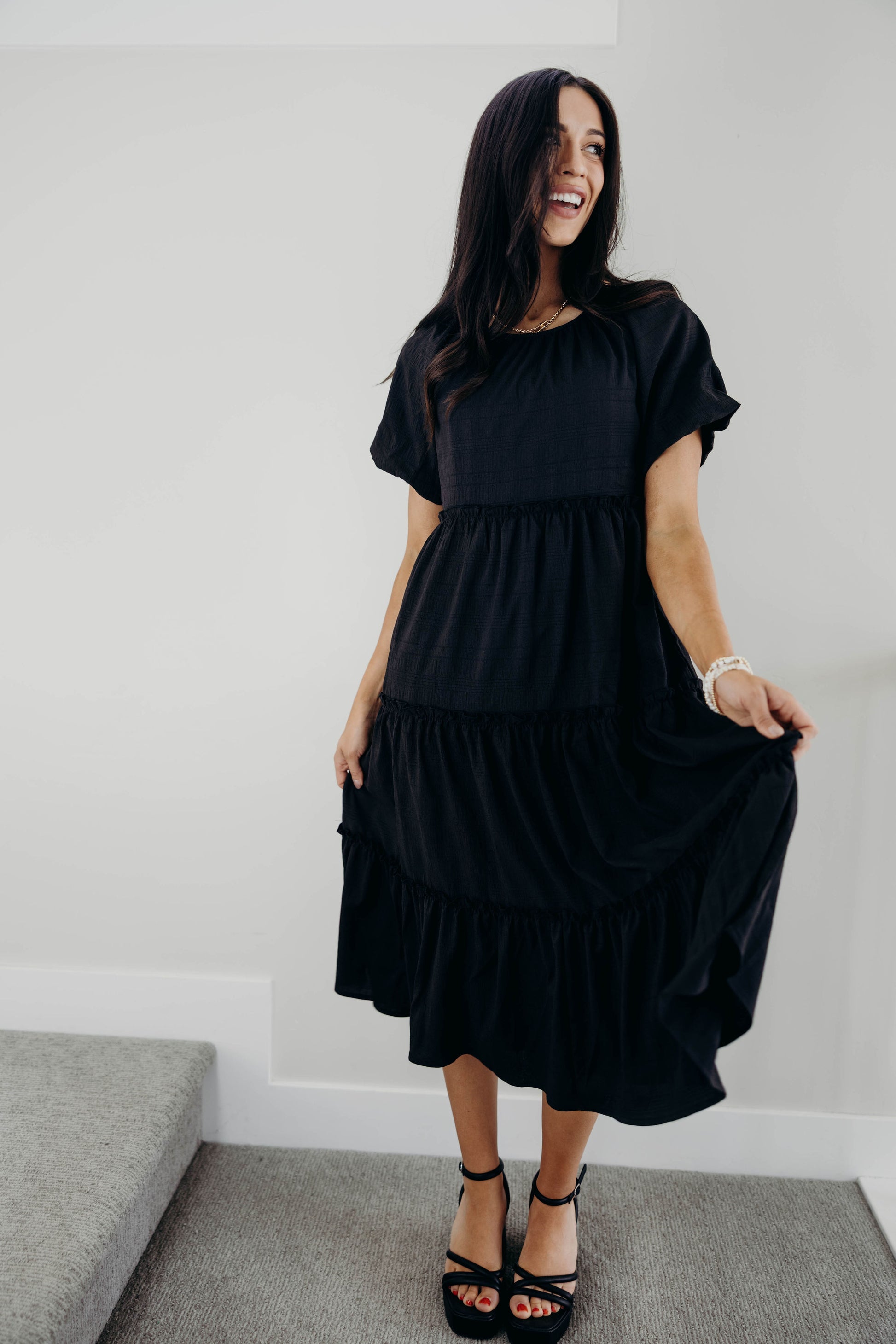 Black midi dress with round neckline and short sleeves.