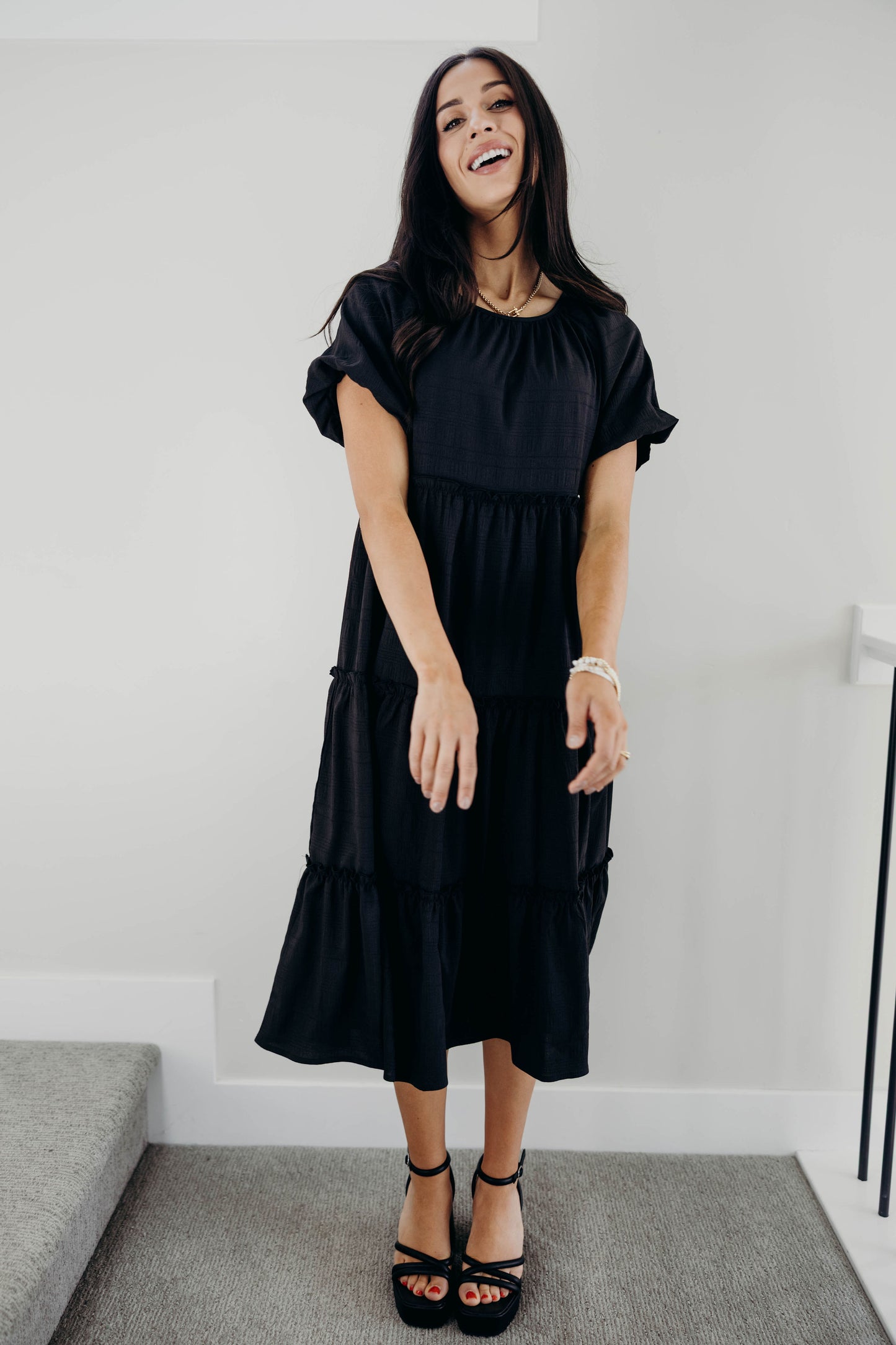 Black tiered dress with ruffle detail on tiers, short sleeves and round neckline.