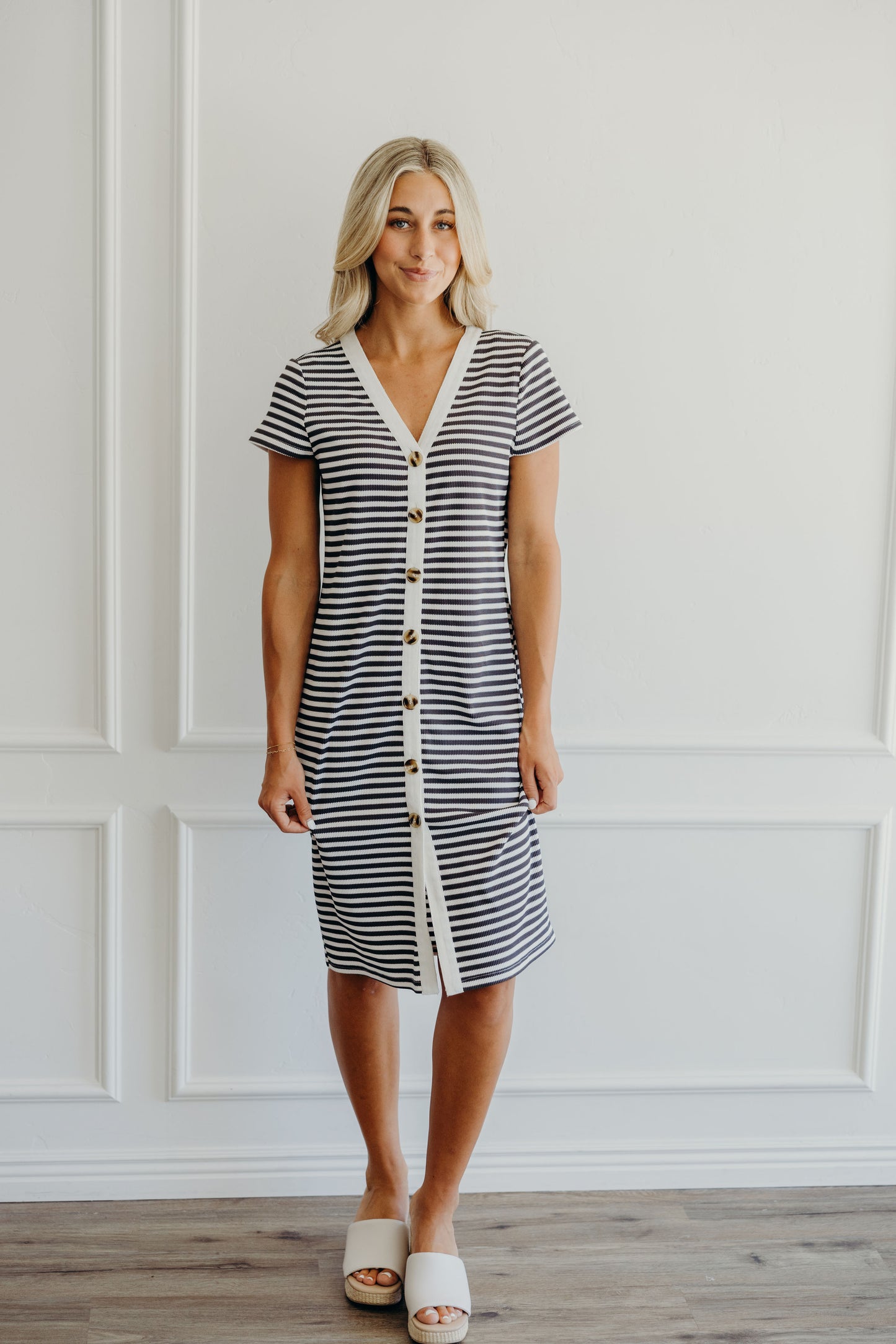 Knee length ribbed striped dress with short sleeves, button detail, and striped fabric.