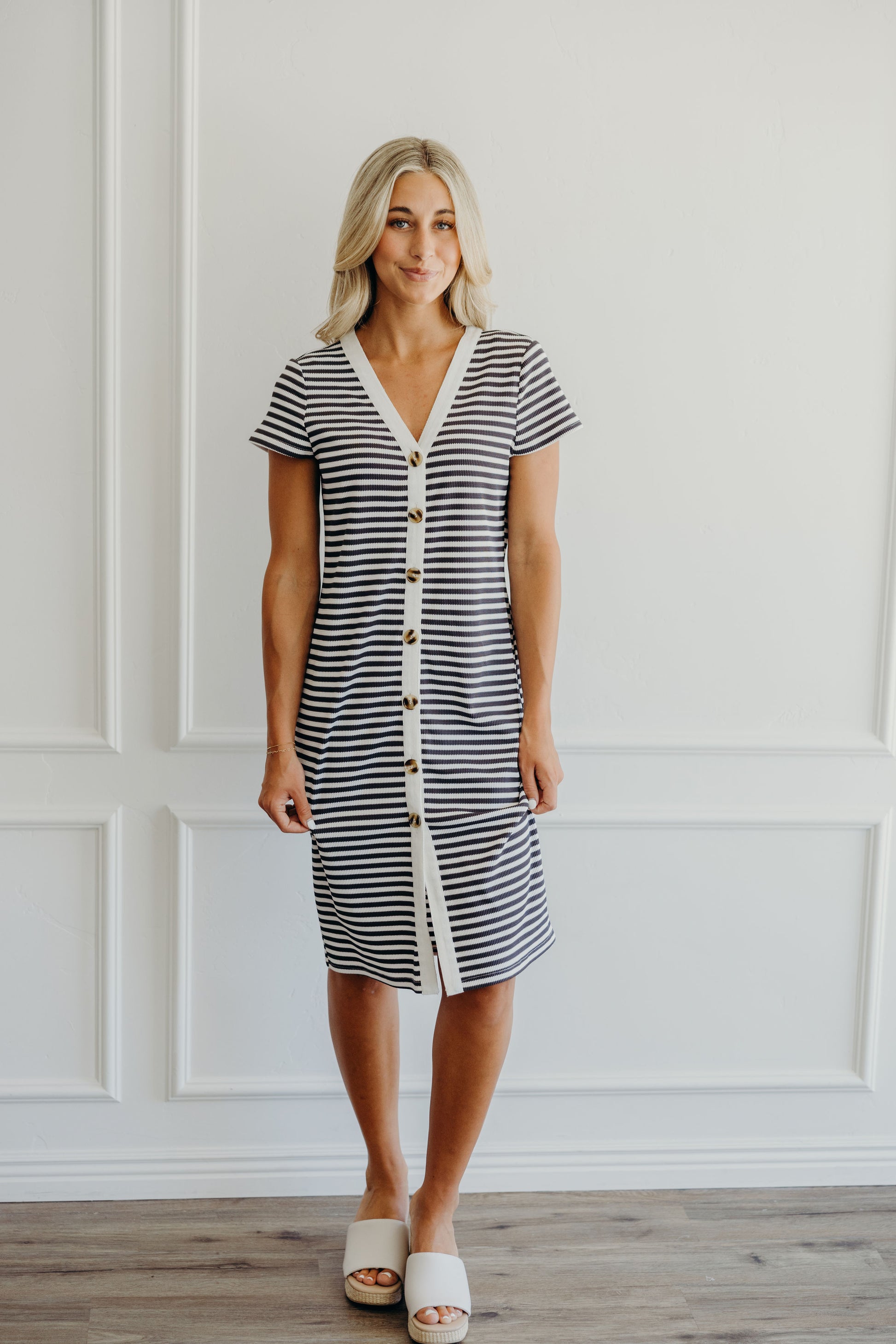 Knee length ribbed striped dress with short sleeves, button detail, and striped fabric.