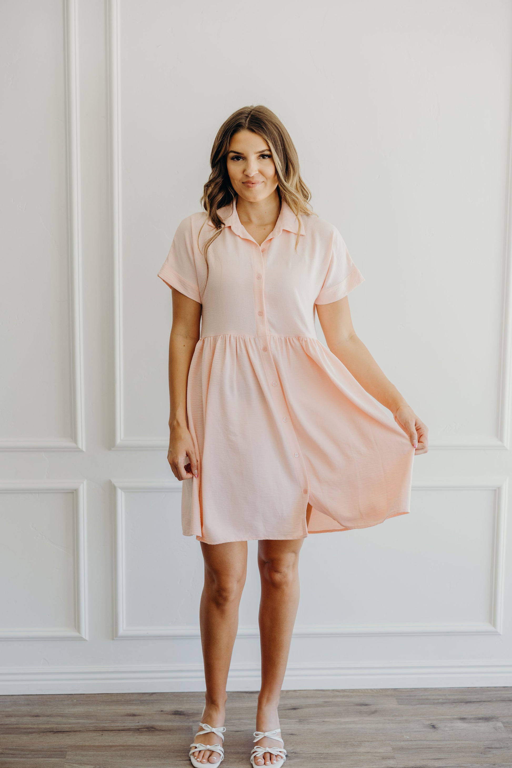 Pink knee length button down dress with natural waistline and collar detail.