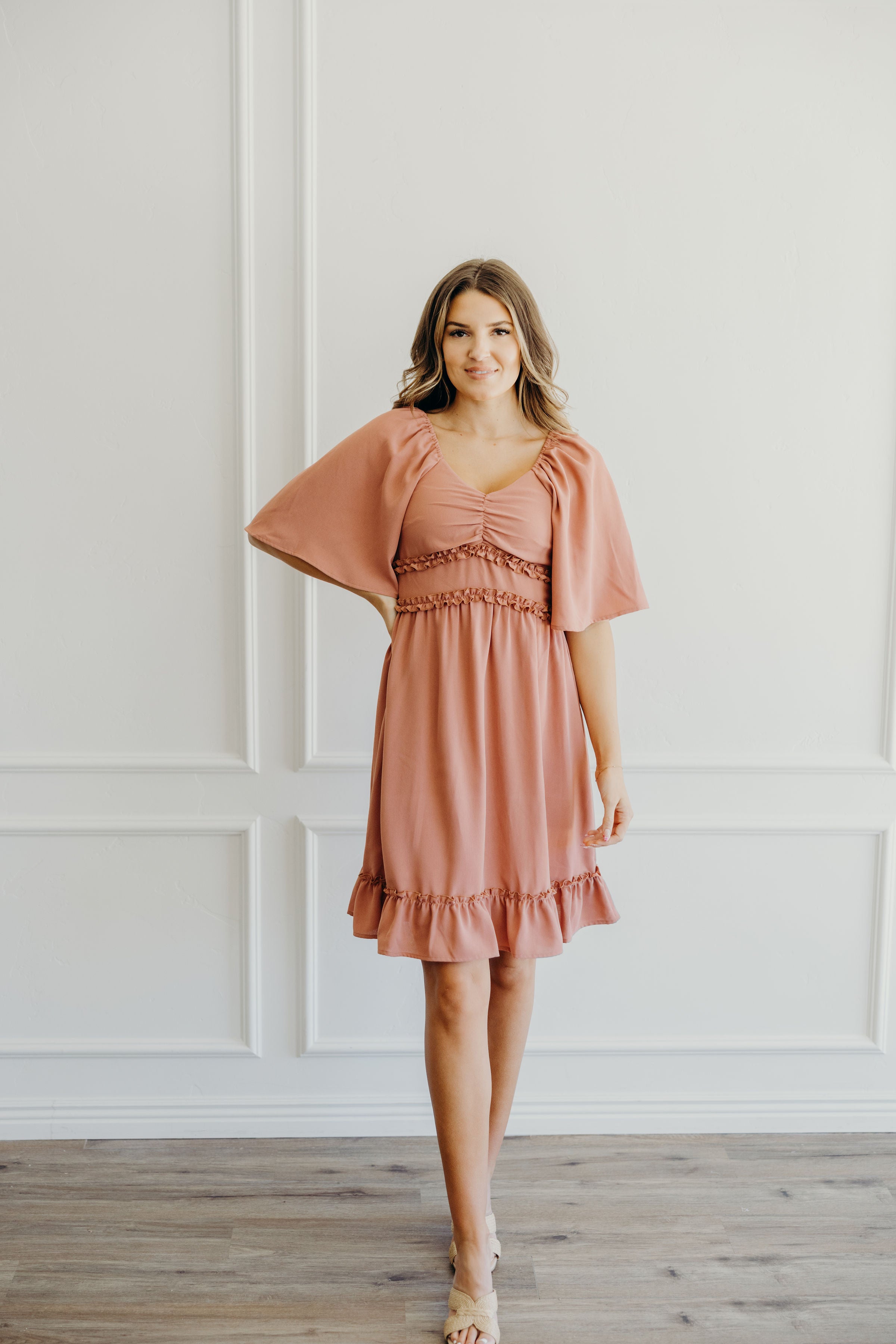 Short fit and flare dark pink dress with ruffle hem, ruffle detail at waist, sweetheart neckline and oversized flutter sleeves.