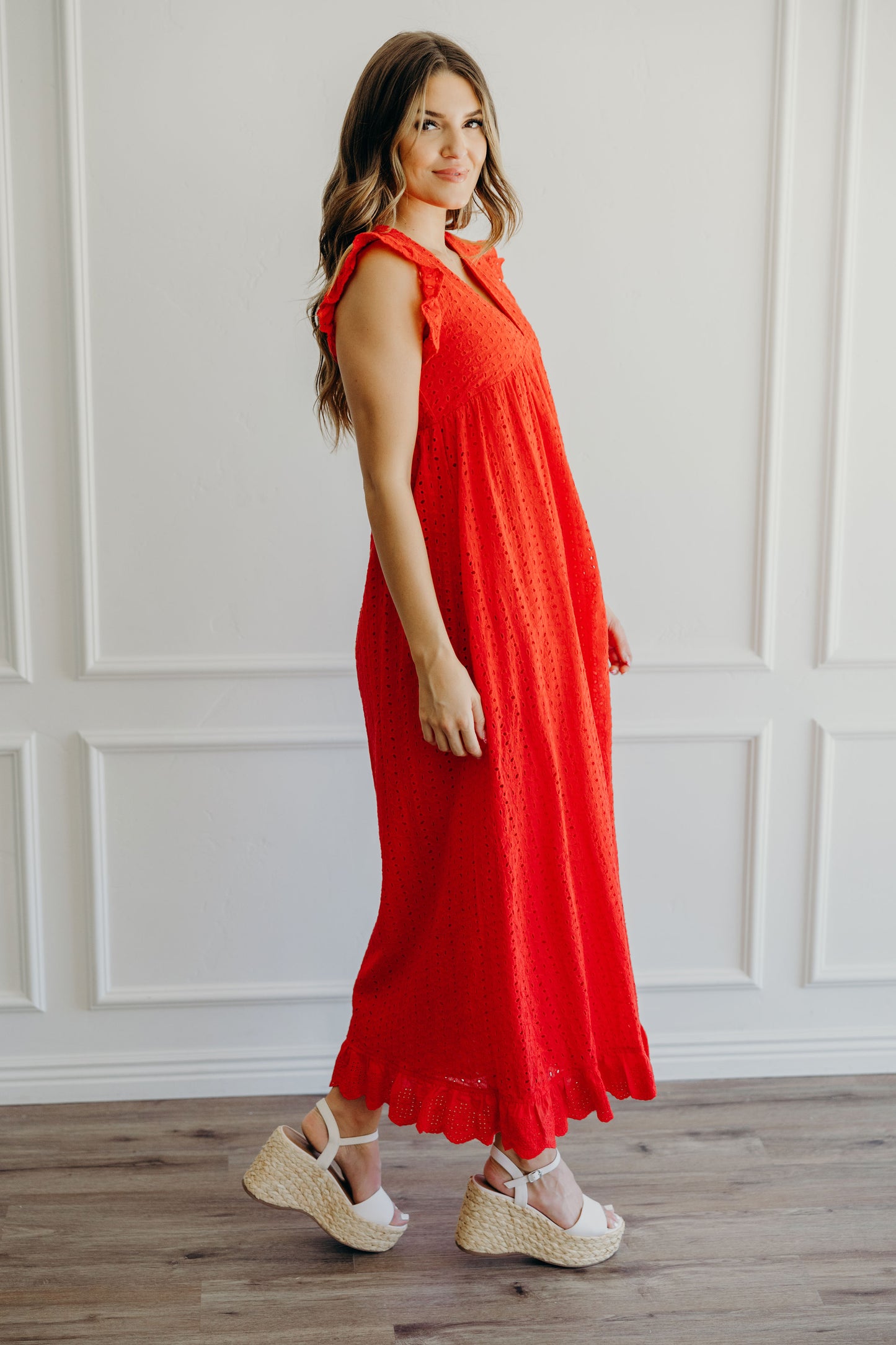 Full length red dress with empire waist line and flutter sleeve and decorative hem.