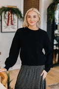 OVERSIZED SWEATER in black, long sleeve, featured in the 2026 Fall Collection, styled with a patterned skirt.