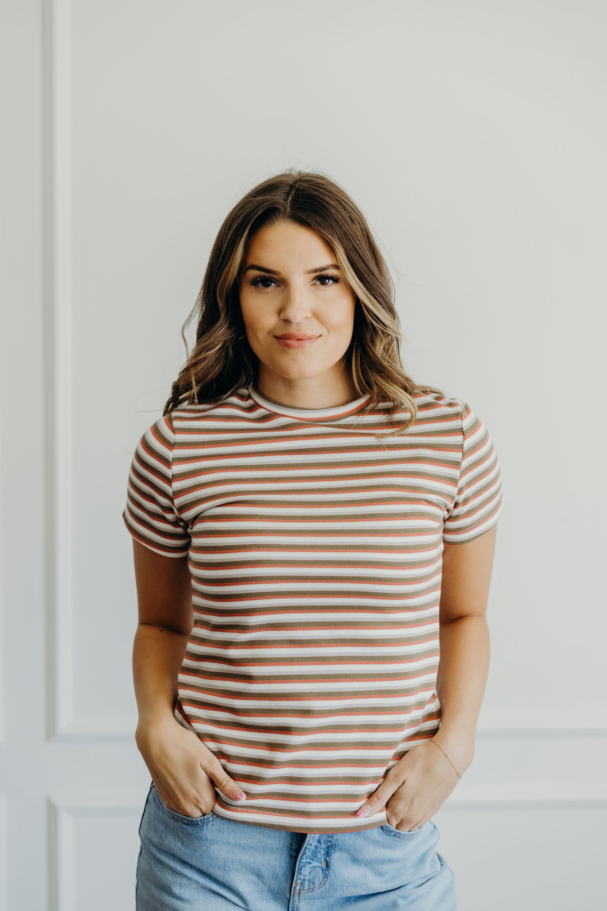 High neck tee with short sleeves and pink, cream, green, and gray stripes.