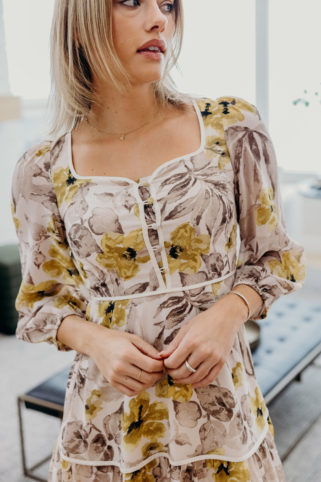 Cream and gray floral print dress with piping and button detail.