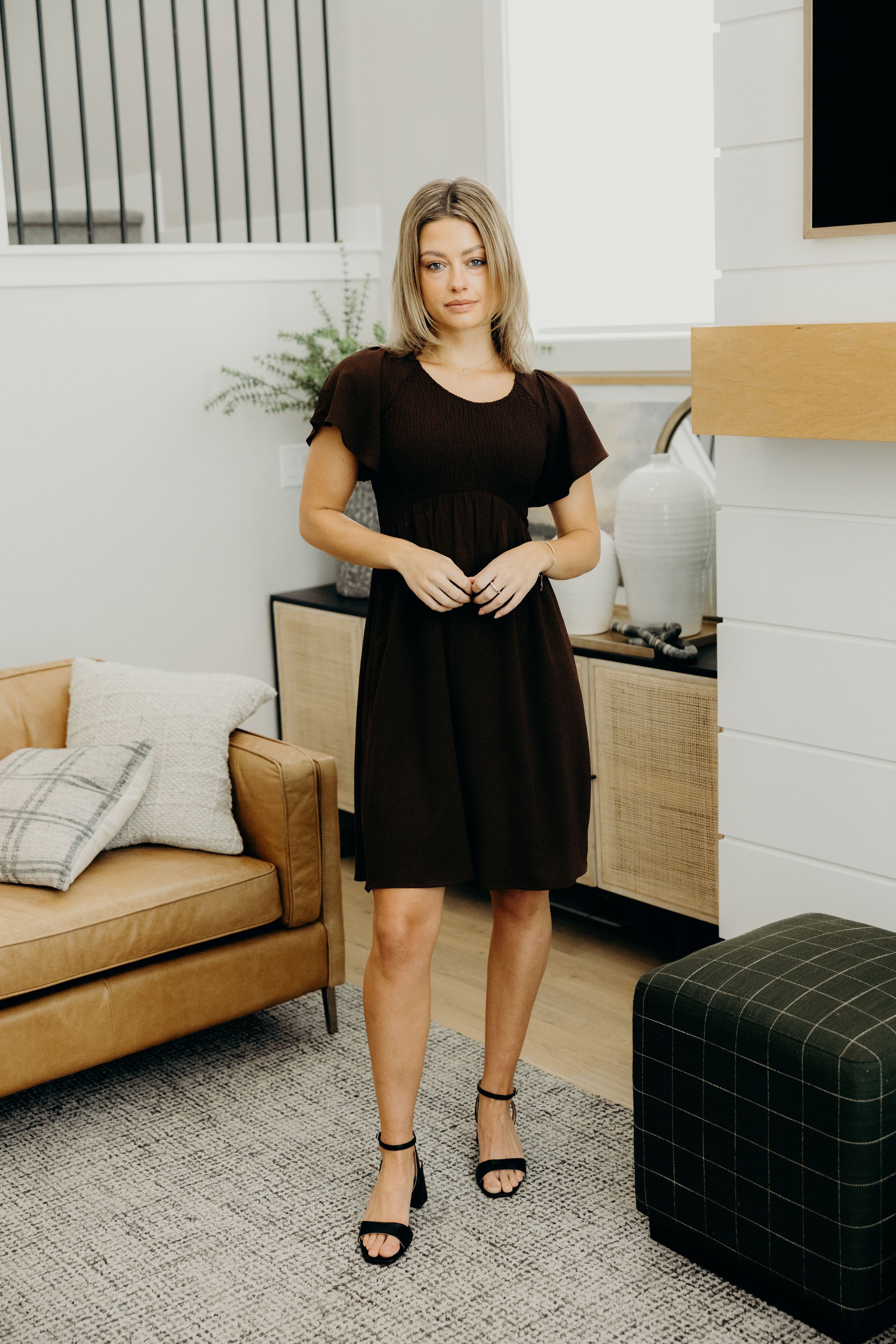 Knee length dark brown dress with smocked bodice and flutter sleeves.