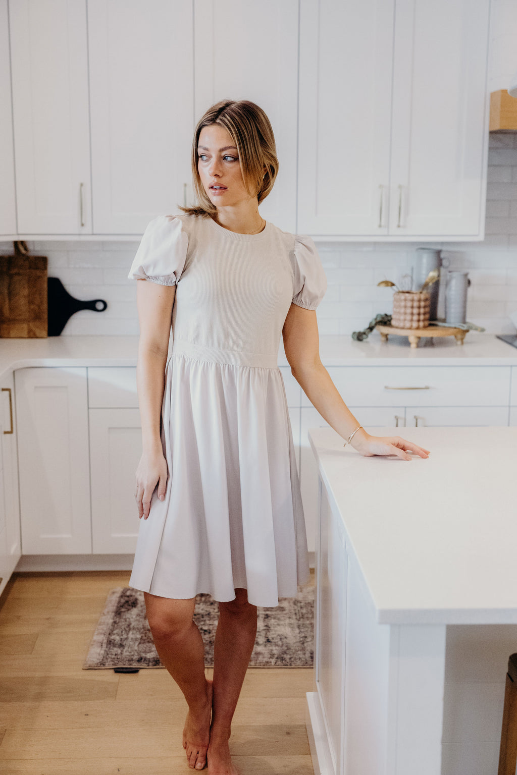Knee length cream dress with textured bodice, and short sleeves.