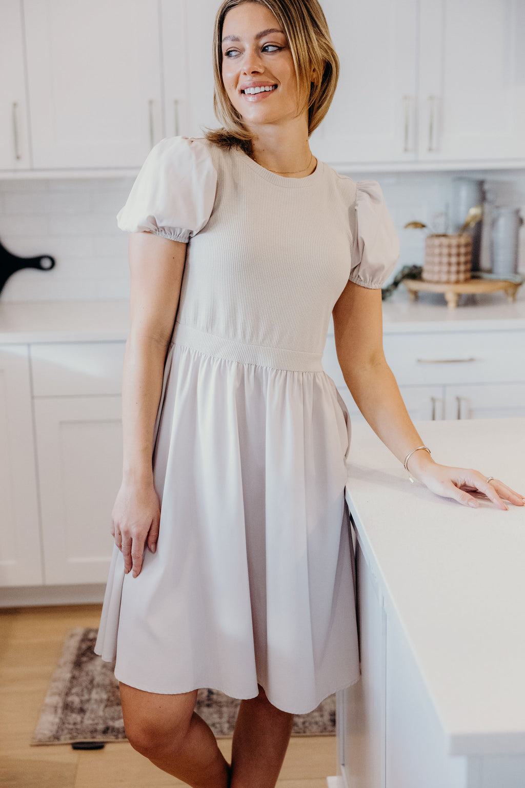 Vanilla dress with waffle texture bodice, short sleeve, high neckline, and knee length skirt.