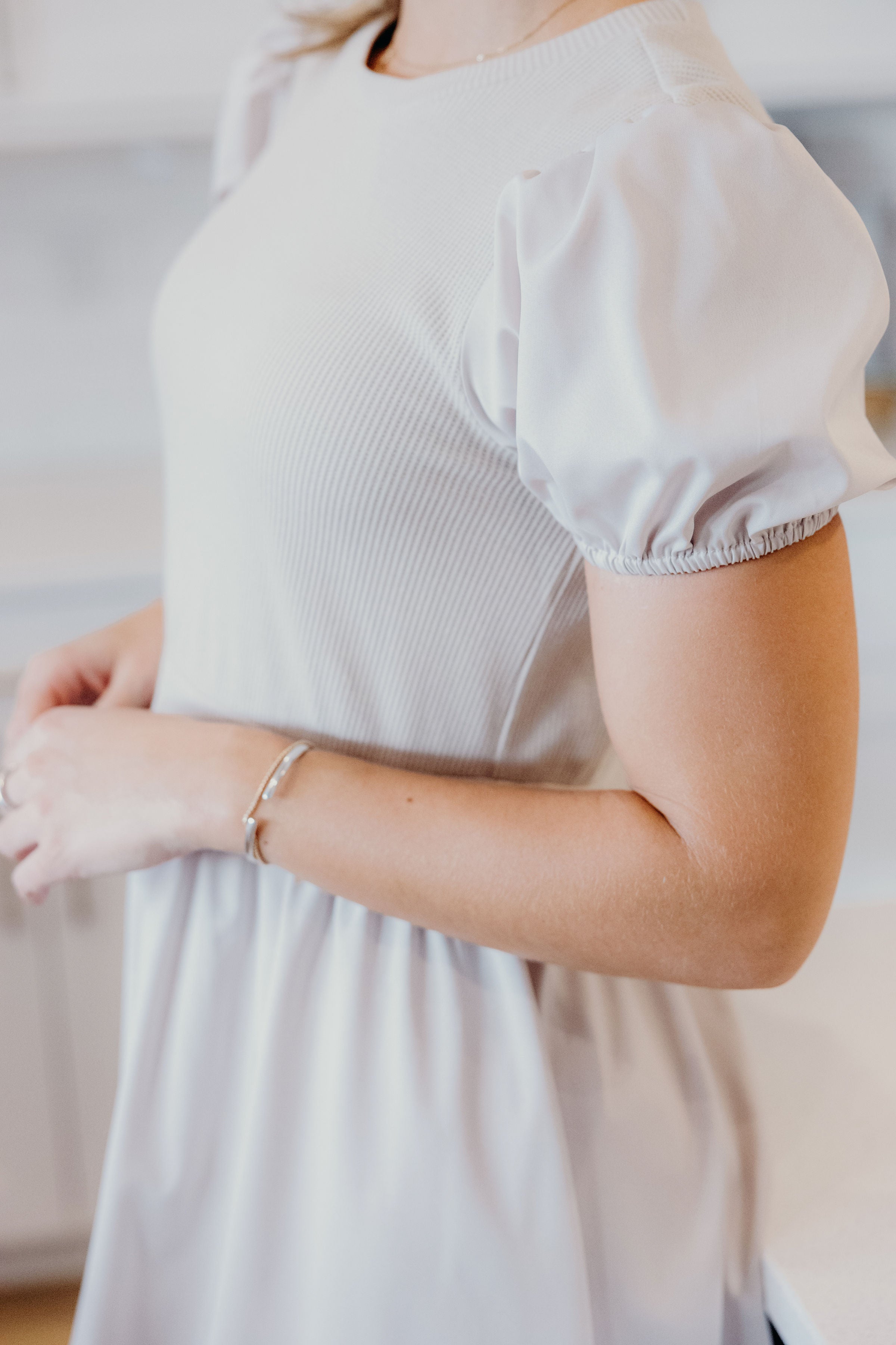 Detail view of bodice with waffle textured bodice and short puff sleeves.