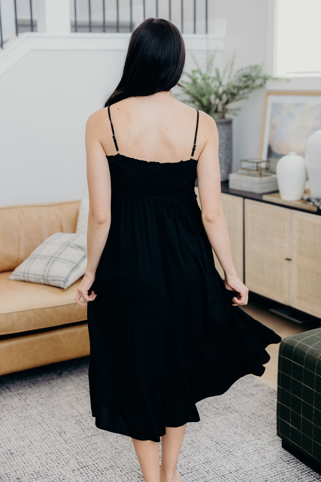 Back view of black tank dress with smocked bodice with ruffle hem.