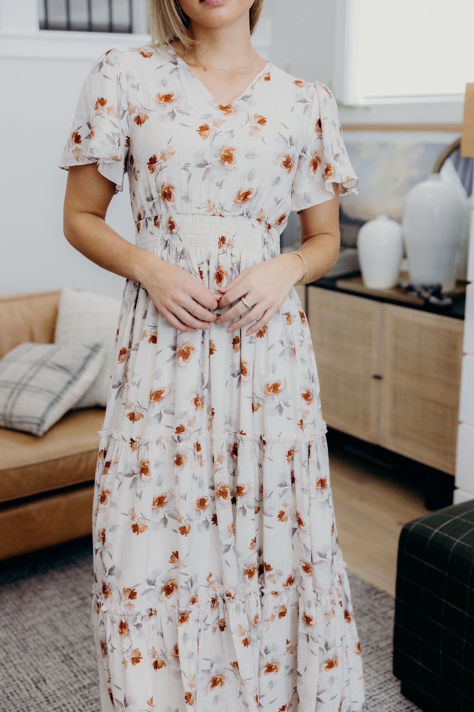 Cream print dress with smocked waist, tiered skirt, and flutter sleeves.
