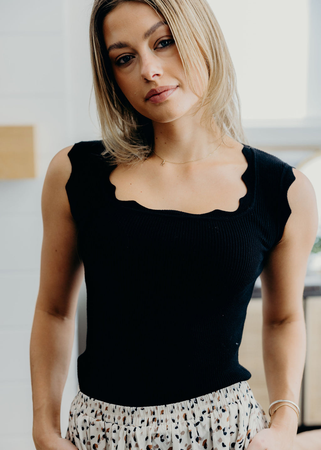 Black sweater tank with scallop edging on neckline and shoulders.