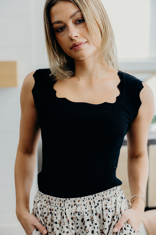 Black sweater tank with scallop edging on neckline and shoulders.