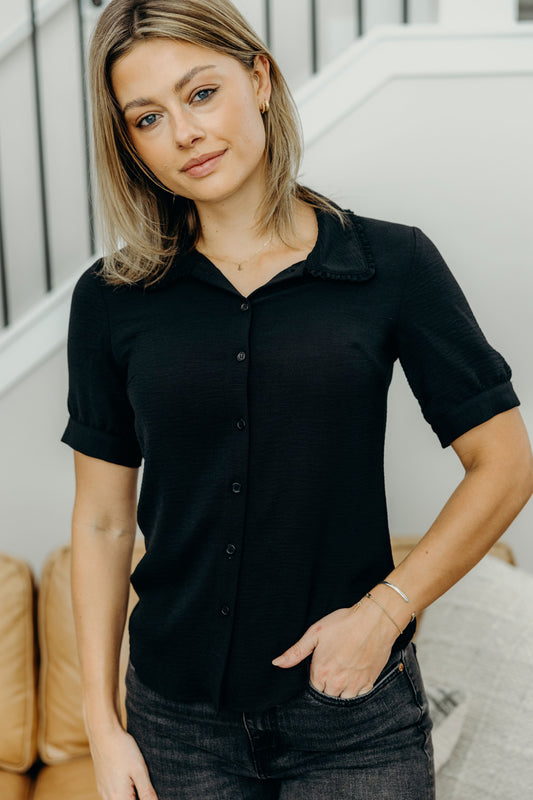 Black collared top with ruffle detail on collar and buttons down the front.