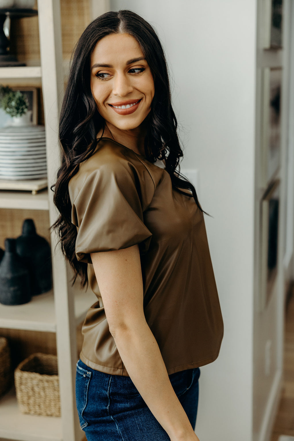 Side view of brown faux leather top with puff sleeve.