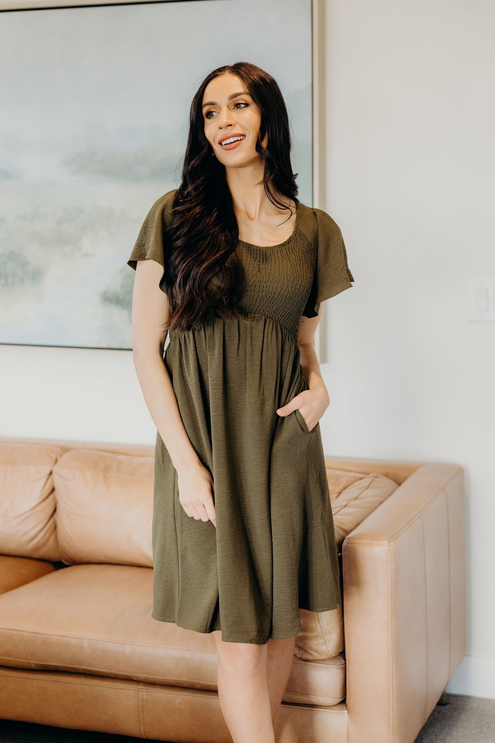 Green knee length dress with smocked bodice and v neckline with pockets.