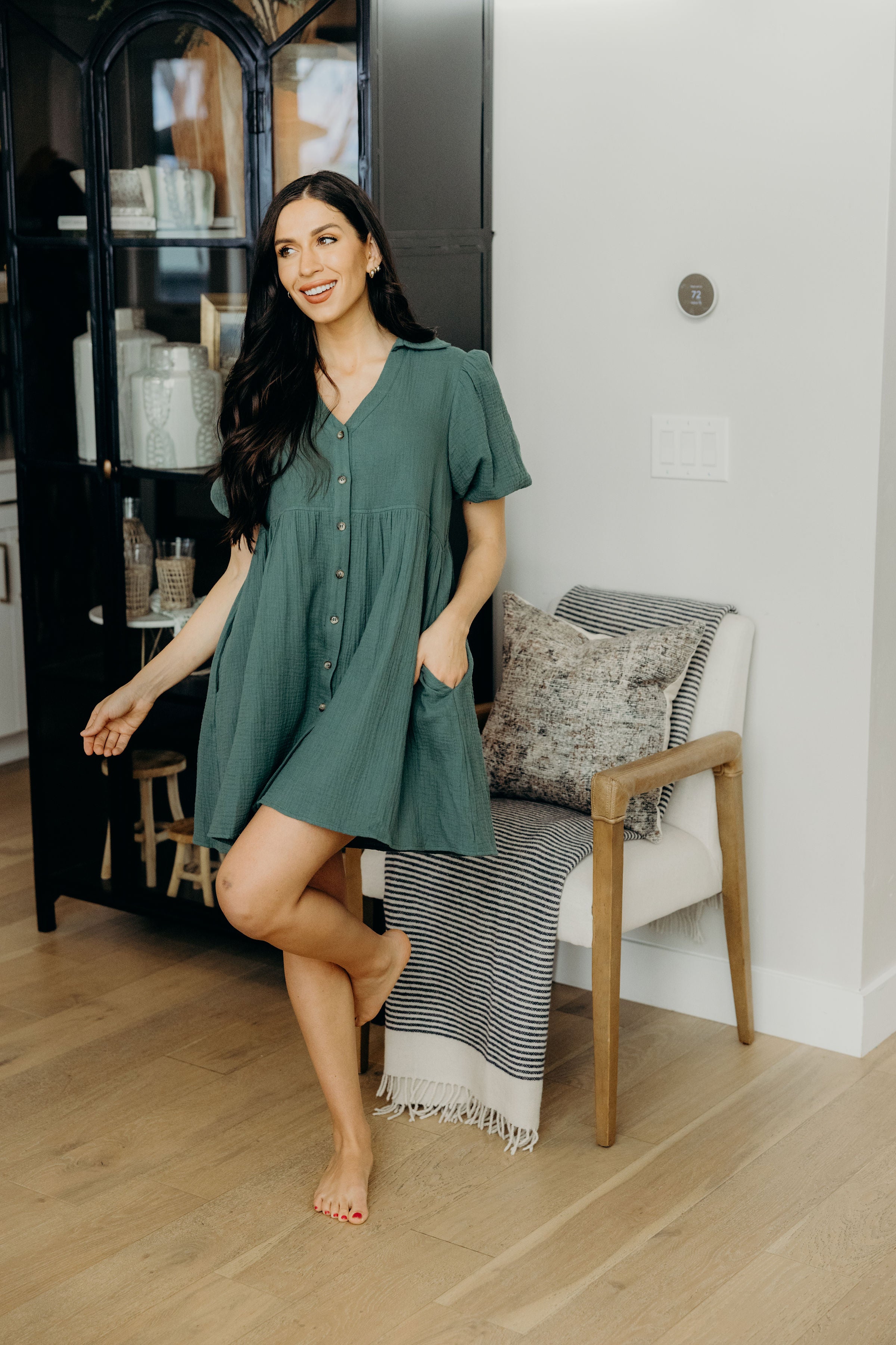 Knee length green dress with button down front, v neckline, and pockets.