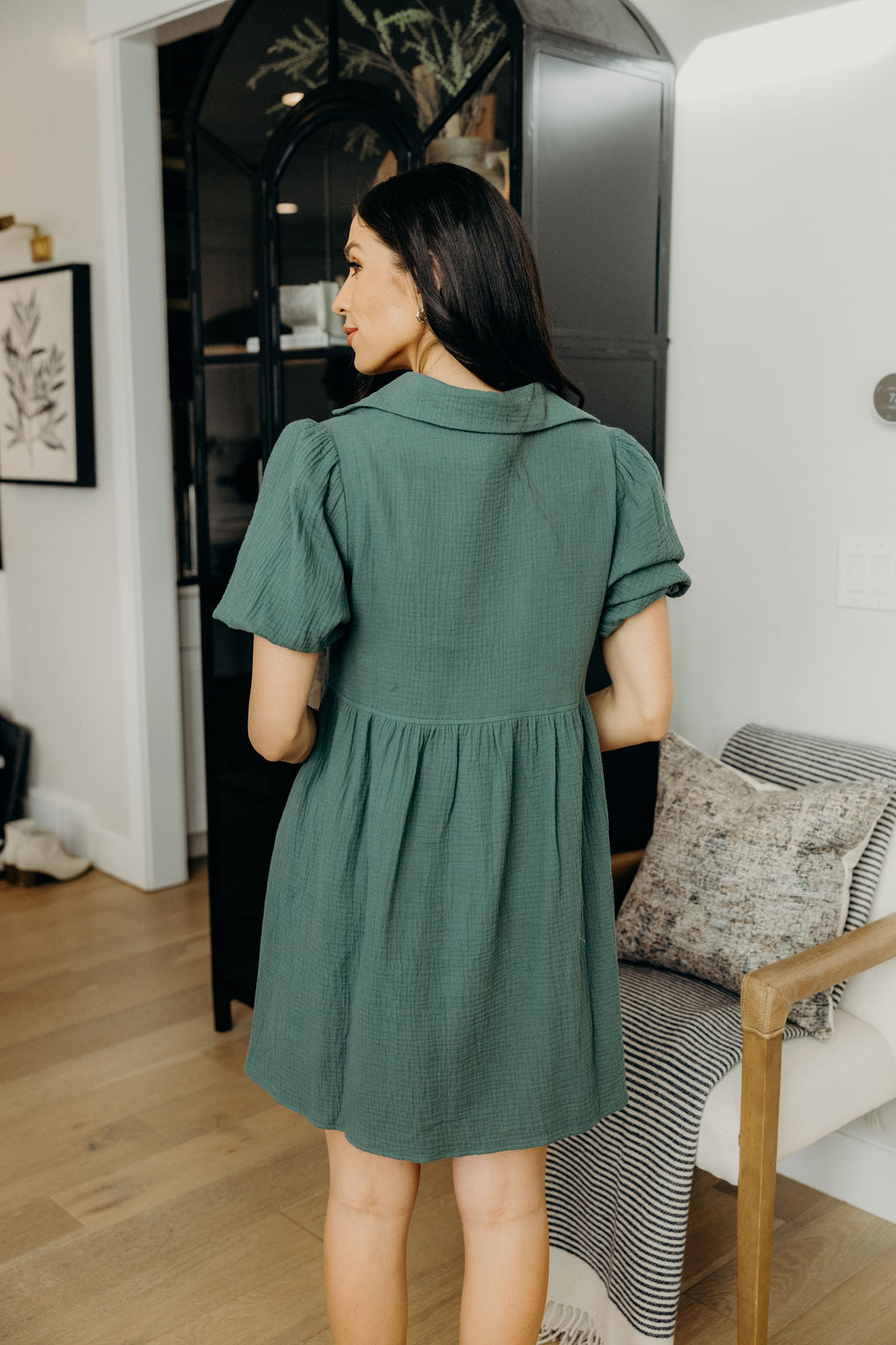 Back view of green dress with natural waistline, short puff sleeves and collar detail.