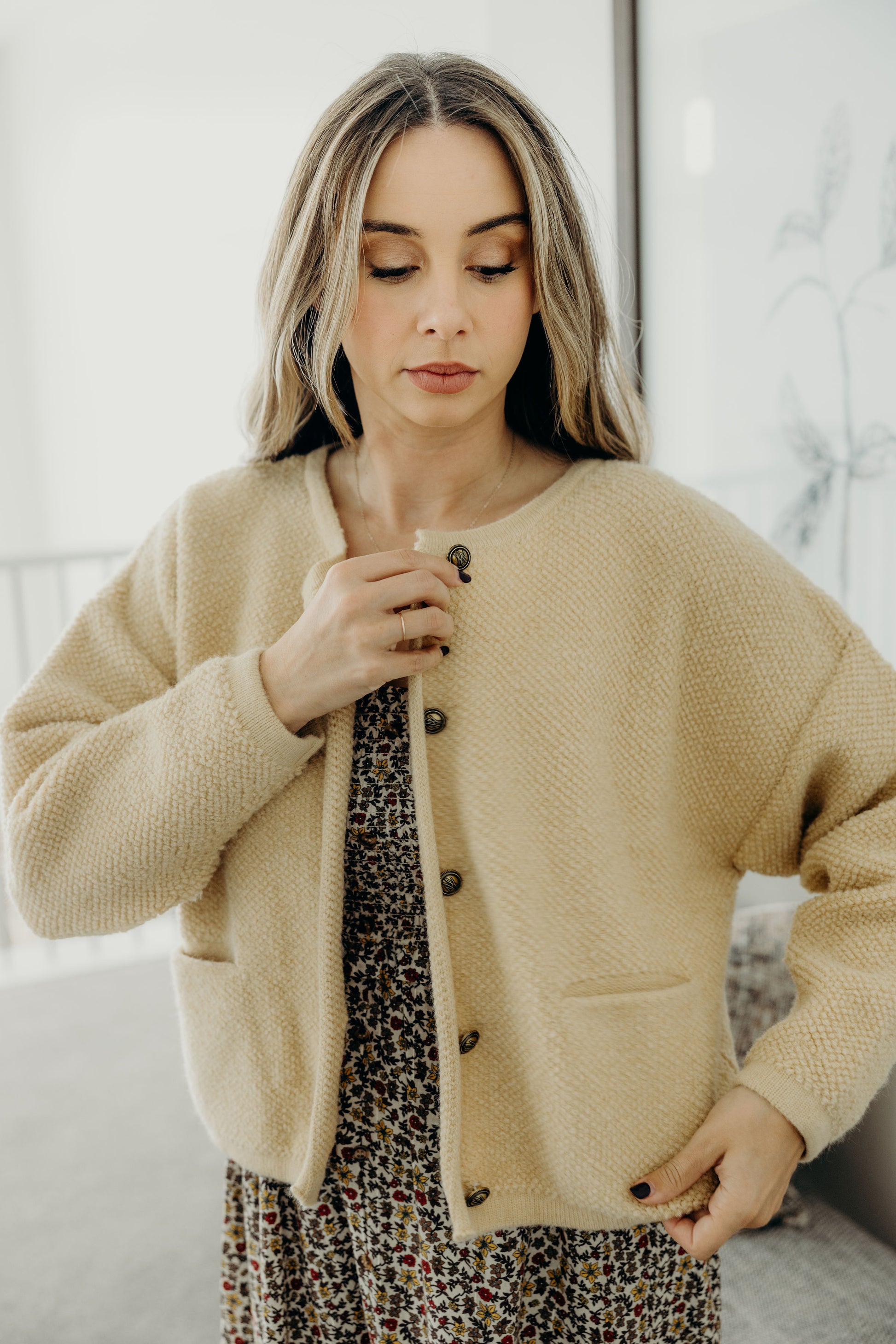 Knit textured cornsilk with front pockets, brass buttons and round neckline.